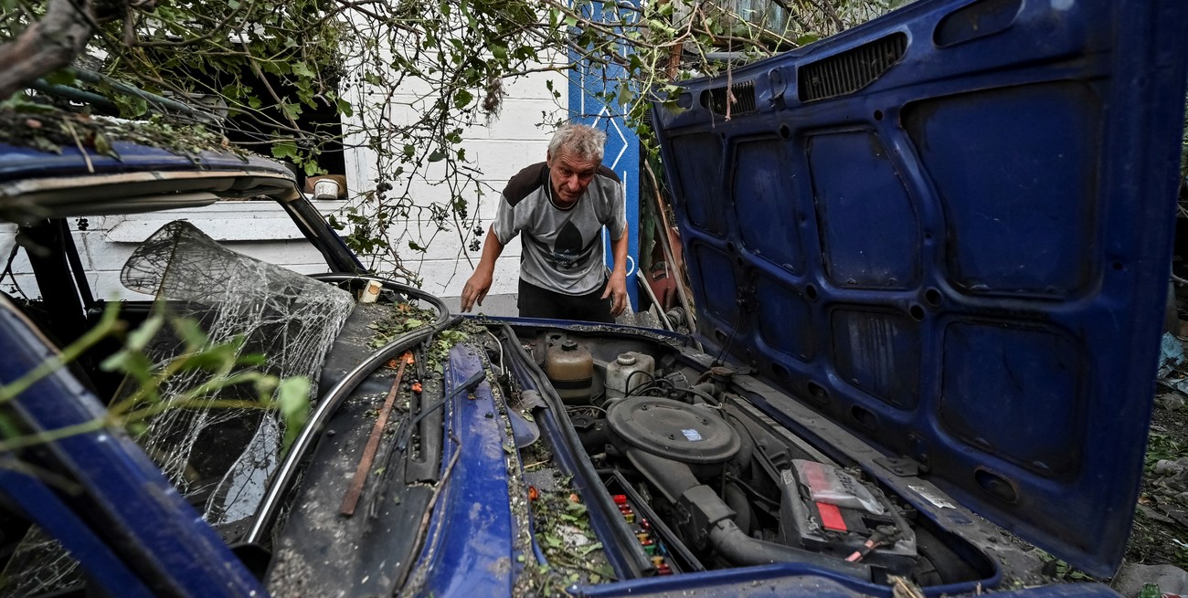 Un hombre se muestra junto a su automóvil, destruido tras el ataque militar ruso. Crédito: Reuters