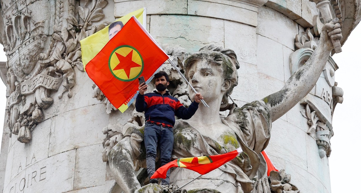 Un hombre sostiene una bandera del Partido de los Trabajadores del Kurdistán (PKK), mientras miembros de la comunidad kurda se reúnen en la Plaza de la Republica . Crédito: Sarah Meyssonnier / Reuters