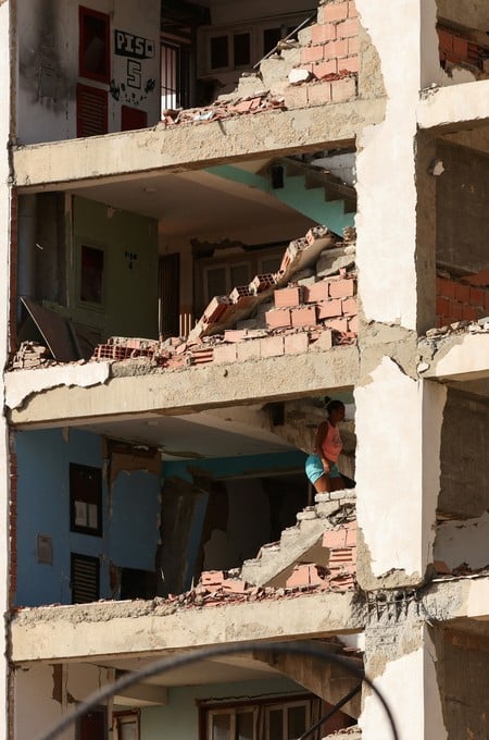 A woman climbs the stairs of a damaged building, as Venezuelans face worsening power and water shortages following government warnings of drought linked to the El Nino phenomenon, deepening hardships for a population already coping with daily outages and the aftermath of devastating earthquakes, in La Guaira, Venezuela, August 7, 2026. REUTERS/Leonardo Fernandez Viloria