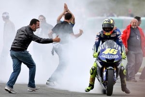 FILE PHOTO: Motorcycling fans cheer for Italy's Valentino Rossi as he smokes his motorcycle tyre after winning Czech Grand Prix in Brno.  Motorcycling fans cheer for Italy's Valentino Rossi as he smokes the tyre of his Yamaha after winning the Czech Grand Prix MotoGP race at Masaryk's circuit in Brno, August 28, 2005. World Champion Rossi took the chequered flag at the Czech Grand Prix on Sunday, winning a game of cat and mouse with Spanish rival Sete Gibernau, who failed to finish after a mechanical problem on the last lap. REUTERS/David W Cerny/File Photo