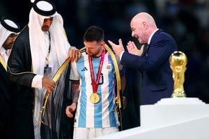 Soccer Football - FIFA World Cup Qatar 2022 - Final - Argentina v France - Lusail Stadium, Lusail, Qatar - December 18, 2022 
 A robe is put on Argentina's Lionel Messi by Emir of Qatar Sheikh Tamim bin Hamad Al Thani as FIFA president Gianni Infantino looks on during the trophy ceremony REUTERS/Hannah Mckay