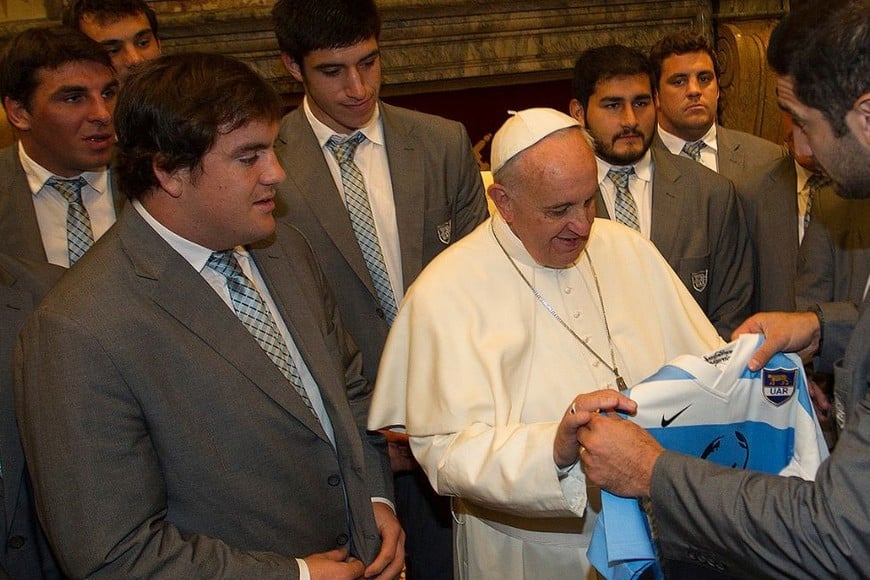 A la izquierda de la imagen, el santafesino Maximiliano Bustos mira con atención el momento en el que el capitán de Los Pumas, Juan Manuel leguizamón, le entrega una camiseta al Papa Francisco.
