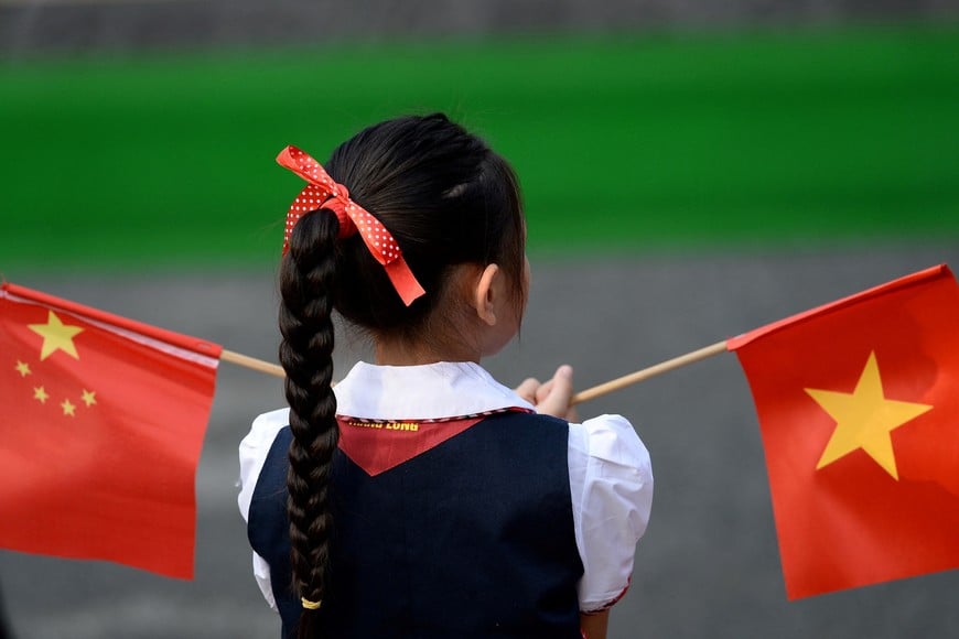 FILE PHOTO: A Vietnamese pupil holds Chinese and Vietnamese flags before a welcoming ceremony for China's President Xi Jinping at the Presidential Palace in Hanoi, Vietnam, Nov. 12, 2017. REUTERS/Hoang Dinh Nam/Pool/File Photo