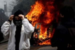 Masked protesters stand in front of a burning car during clashes at a demonstration as part of the tenth day of nationwide strikes and protests against French government's pension reform in Nantes, France, March 28, 2023.   REUTERS/Stephane Mahe