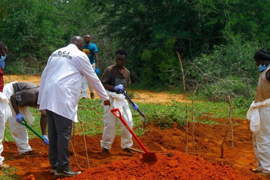 Los voluntarios ayudan a expertos forenses y detectives de homicidios de la Dirección de Investigaciones Criminales (DCI) a exhumar los cuerpos de presuntos seguidores de un culto cristiano. Créditos: Joseph Okanga/ Reuters