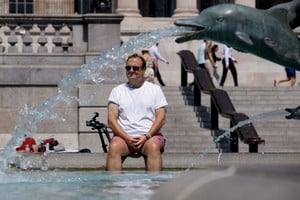 FILE PHOTO: A man cools off in a fountain during the hot weather in London, Britain, July 18, 2022. REUTERS/John Sibley/File Photo