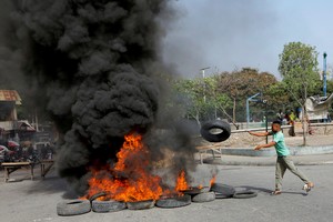 FILE PHOTO: A demonstrator throws a tyre on a burning road block as anger mounted over fuel shortages that have intensified as a result of gang violence, in Port-au-Prince, Haiti, July 13, 2022. REUTERS/Ralph Tedy Erol REFILE - QUALITY REPEAT/File Photo