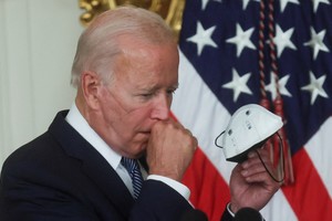 U.S. President Joe Biden takes off his protective face mask worn because of the COVID-19 pandemic before speaking at a ceremony where he signed "The Inflation Reduction Act of 2022" into law in the State Dining Room of the White House in Washington, U.S. August 16, 2022. First lady Jill Biden tested positive for COVID-19 earlier in the day.   REUTERS/Leah Millis