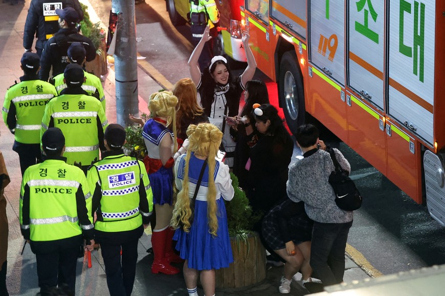 Partygoers gather near a fire truck at the scene where dozens of people were injured in a stampede during a Halloween festival in Seoul, South Korea, October 30, 2022. REUTERS/Kim Hong-ji REFILE - CORRECTING DATE