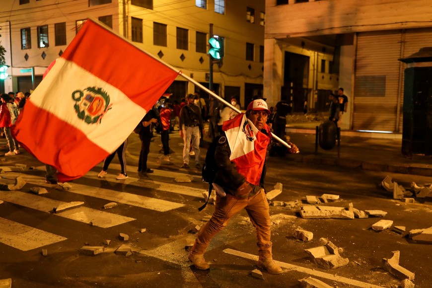 A demonstrator carries Peru's flag during a protest demanding the dissolution of Congress and to hold democratic elections rather than recognize Dina Boluarte as Peru's President, after the ouster of Peruvian leader Pedro Castillo, in Lima, Peru December 11, 2022. REUTERS/Sebastian Castaneda