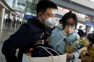 La gente se abraza en la puerta de llegadas internacionales del Aeropuerto Internacional Capital de Beijing después de que China levantara el requisito de cuarentena de la enfermedad por coronavirus para los viajeros entrantes en China. Créditos: Thomas Peter/ Reuters