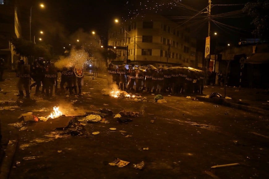 Police officers take cover as people take part in an anti-government demonstration following the ouster of Peru's former President Pedro Castillo, in Lima, Peru January 26, 2023. REUTERS/Sebastian Castaneda