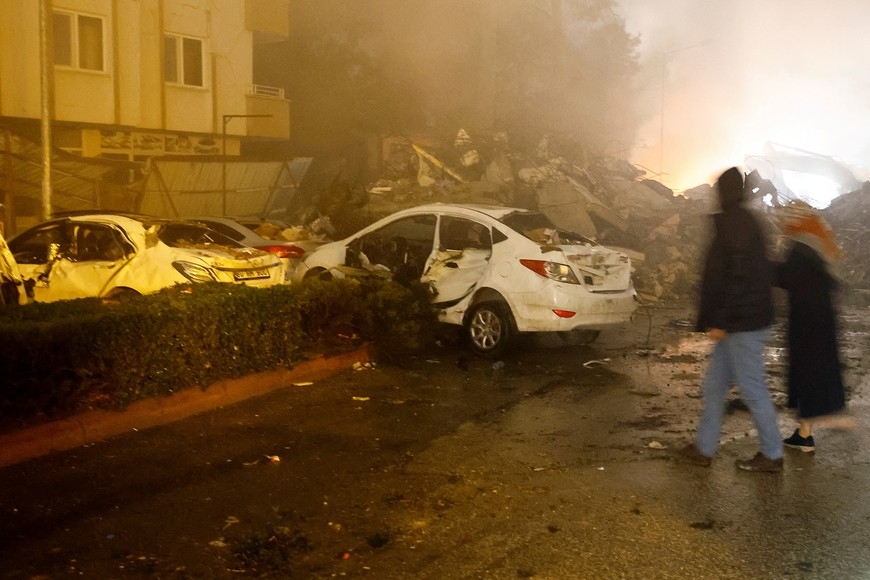People walk near destroyed cars, following an earthquake, in Osmaniye, Turkey, February 6, 2023. REUTERS/Suhaib Salem
