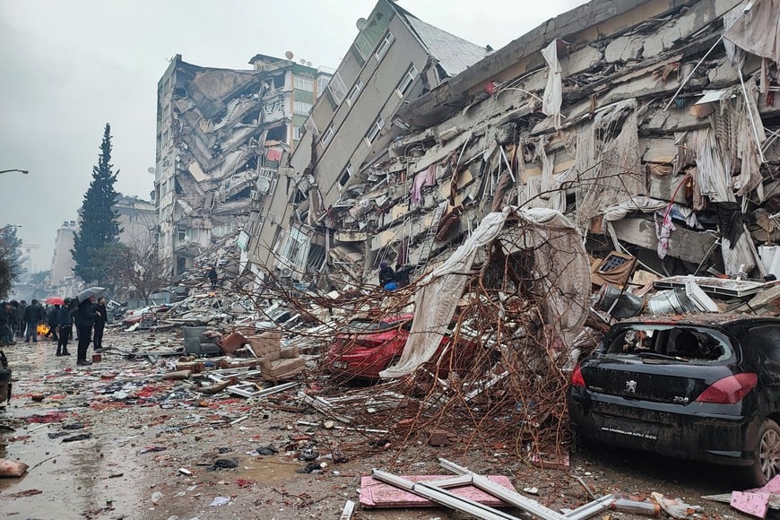 People stand in front of collapsed buildings following an earthquake in Kahramanmaras, Turkey February 6, 2023. Ihlas News Agency (IHA) via REUTERS ATTENTION EDITORS - THIS PICTURE WAS PROVIDED BY A THIRD PARTY. NO RESALES. NO ARCHIVES. TURKEY OUT. NO COMMERCIAL OR EDITORIAL SALES IN TURKEY.