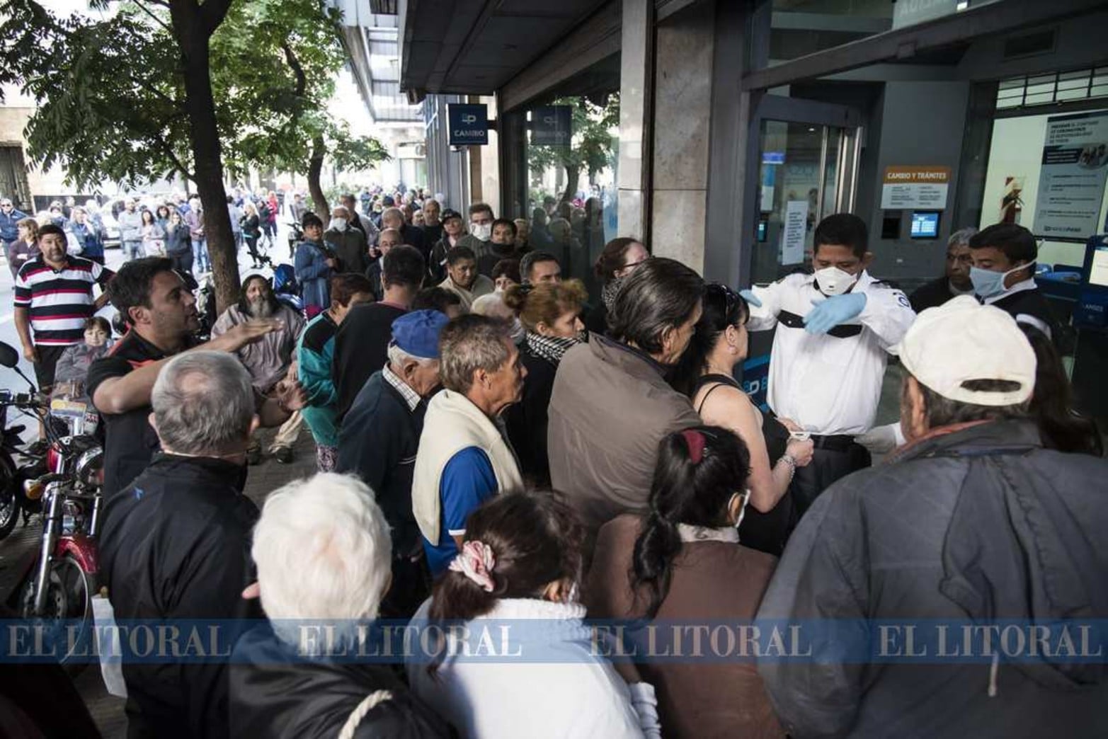 De no creer. Un guardía intenta, sin lograr, que las personas tomen distancia en la puerta de un banco en Rosario.