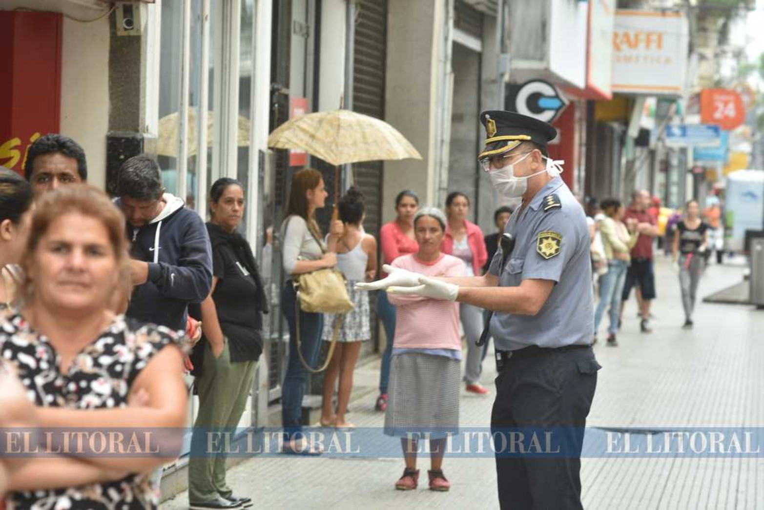 27 de marzo. Solo siete días de la cuarentena. Distanciamiento por favor se ve pedir al policía en la cola para ingresar a los cajeros.