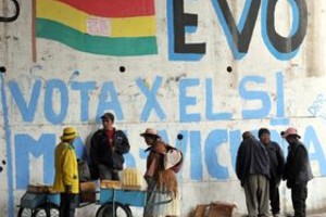 AFP People stand next to a wall with graffitis supporting the new Constitution proposed by Bolivian President Evo Morales in El Alto, on January 23, 2009. Voters in Bolivia are to go to the polls on January 25 to decide a referendum on changing their constitution that will pit the indigenous majority backing Morales against the economic elite of European descent.  AFP PHOTO/AIZAR RALDES