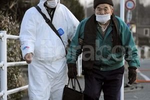 ELLITORAL_39612 |  EFE Un hombre con traje protector acompaña a un anciano mientras es evacuado a un refugio cerca de la central nuclear de Daiichi, en la localidad de Futaba, en la prefectura de Fukushima.