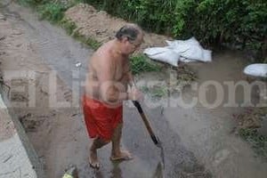 ELLITORAL_117097 | Mauricio Garín En Villa California, los vecinos que viven junto a la ruta 1 limpiaban el desagüe para que el agua escurra. Dicen que antes de la obra no se inundaban.