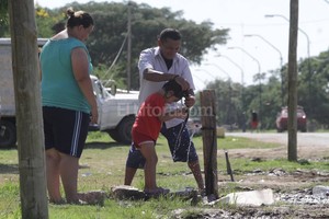 ELLITORAL_144078 |  Mauricio Garín Calor que sofoca. Un hombre refresca a una niña bajo el sol. Por las pérdidas en las canillas se generan charcos.