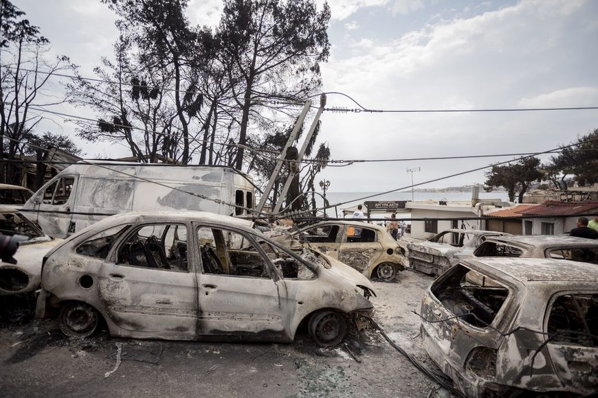 ELLITORAL_217701 |  dpa Vecinos supervisan una zona arrasada por los incendios forestales el 24/07/2018 en Mati, Grecia. Los incendios forestales que se desataron en los alrededores de Atenas, en Grecia, dejaron al menos 50 muertos, después de que esta madrugara se encontraran otros 26 cadáveres en la zona del puerto de Rafina, informaron el 24/07/2018 la Cruz Roja y el vicealcalde de la región, Girgos Kokkolis. (Vinculado al texto de dpa "Aumentan a 50 los muertos en incendios forestales en Grecia" del 24/07/2018) Foto: Christoph Soeder/dpa +++ dpa-fotografia +++