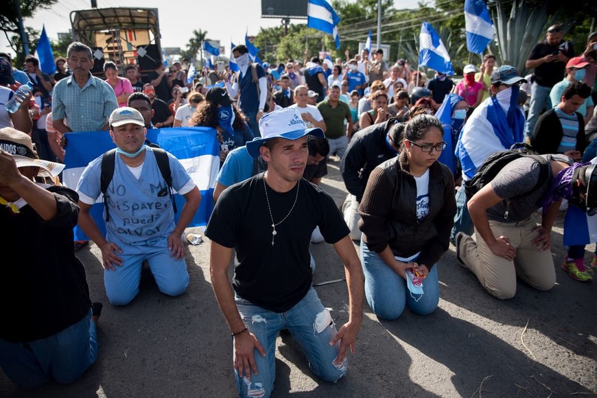 ELLITORAL_217073 |  dpa Manifestantes se arrodillan frente a la policía el 14/07/2018 en Managua, Nicaragua. Las fuerzas de seguridad impidieron el paso de personas que se movilizaban en caravana para reclamar la liberación de unos 200 estudiantes universitarios, sacerdotes y periodistas que permanecían sitiados por parte de paramilitares armados dentro de la iglesia Divina Misericordia.
