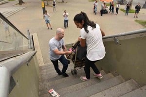 ELLITORAL_277752 |   Ardua tarea. Dos jóvenes suben con dificultad a un niño que está en un cochecito, en la escalera del puente peatonal de Alem y Tucumán.