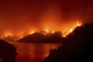 ELLITORAL_321265 |  Noah Berger Flames from the LNU Lightning Complex fires burn around Lake Berryessa in unincorporated Napa County, Calif., on Wednesday, Aug. 19, 2020. Fire crews across the region scrambled to contain dozens of wildfires sparked by lightning strikes. (AP Photo/Noah Berger)