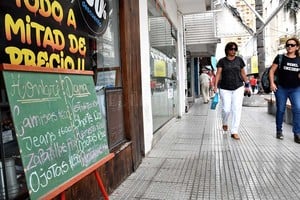 ELLITORAL_237883 |  Flavio Raina. Rebusque. Los clientes revuelven la caja con los calzados al costo, una forma de generar ventas. Promociones. Algunos locales tienen que hacer descuentos hasta del 50% para no tener pérdidas y poder sacarse de en cima la mercadería de la temporada de verano.