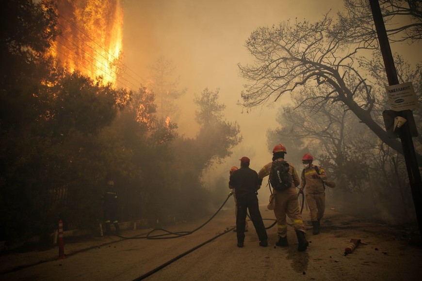 ELLITORAL_217707 |  dpa Los bomberos intentan controlar el incendio en la región de Kinetta, 40 kilómetros al oeste de Atenas, Grecia, el 23/07/2018. Las fuertes sequías favorecieron un incendio forestal que se propagó a raíz de fuertes vientos. Grecia atraviesa un verano con temperaturas de hasta 40 grados. Foto: Eurokinissi/Eurokinissi/dpa +++ dpa-fotografia +++