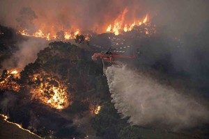 ELLITORAL_278883 |  Agencias In this Monday, Dec. 30, 2019 photo provided by State Government of Victoria, a helicopter tackles a wildfire in East Gippsland, Victoria state, Australia. Wildfires burning across Australia's two most-populous states trapped residents of a seaside town in apocalyptic conditions Tuesday, Dec. 31, and were feared to have destroyed many properties and caused fatalities. (State Government of Victoria via AP)