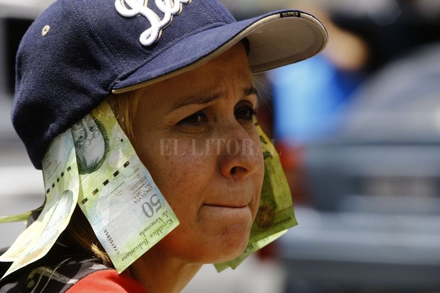 ELLITORAL_221096 |  dpa Venezuela, Valencia: Billetes de 50 bolívares que están fuera de circulación cuelgan de la gorra de una mujer durante una protesta contra la política económica del gobierno.