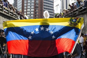 ELLITORAL_225512 |  Archivo Una persona extiende una bandera venezolana ante decenas de manifestantes durante una protesta antigubernamental.