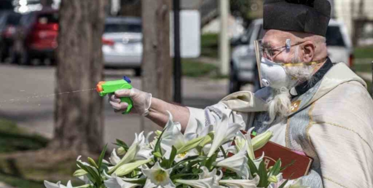 Un sacerdote bendice a los feligreses con una pistola de agua para respetar la distancia social
