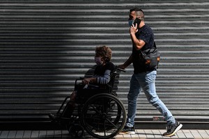 ELLITORAL_365709 |  Xinhua/Jorge Villegas Un hombre traslada a una mujer en silla de ruedas por una calle, en Santiago, capital de Chile.