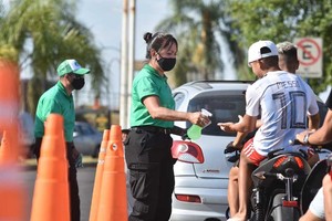 Pablo Aguirre La foto. Dos chicos circulan en moto sin los elementos reglamentarios, una imagen que se repite en todos los barrios de la ciudad. Lo distintivo es que aquí personal municipal los frena? para colocarles alcohol en las manos.