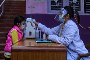 ELLITORAL_343846 |  Xinhua Una médica verifica la temperatura corporal de una estudiante en Katmandú, Nepal, donde algunas escuelas reabrieron después de meses de cierre debido a la pandemia.