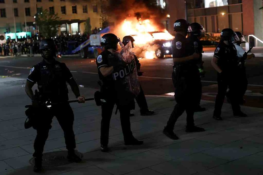 ELLITORAL_305251 |  Agencias Police officers look on as a car burns in the back as protesters continue to rally against the death in Minneapolis police custody of George Floyd, near the White House, in Washington, U.S., May 30, 2020.  REUTERS/Jonathan Ernst