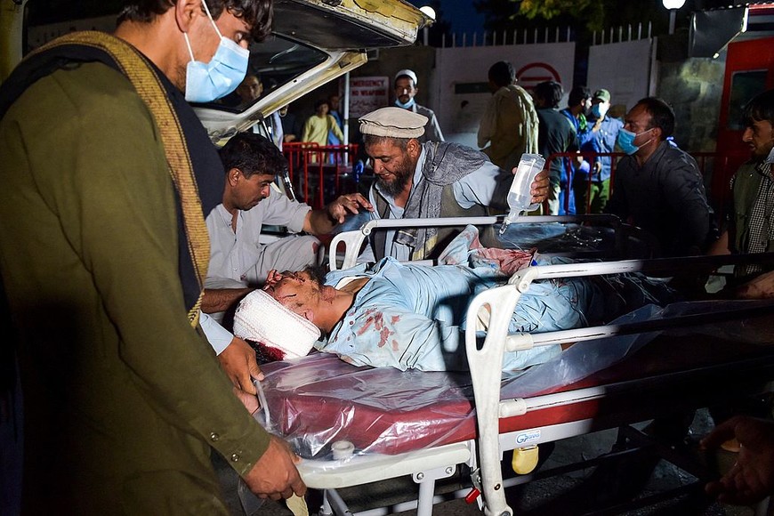 ELLITORAL_399748 |  WAKIL KOHSAR NOTA DEL EDITOR: Contenido gráfico / El personal médico y hospitalario lleva a un hombre herido en una camilla para recibir tratamiento después de dos explosiones, en las que murieron al menos cinco e hirieron a una docena, fuera del aeropuerto de Kabul el 26 de agosto de 2021. (Foto de Wakil KOHSAR / AFP)