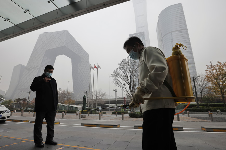 ELLITORAL_415785 |  Reuters A man sprays disinfectant in front of a shopping mall in the Central Business District on a polluted day in Beijing, China, November 5, 2021.  REUTERS/Thomas Peter
