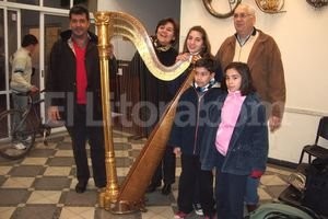 Gentileza Escuela de Música Nº 9.901 La profesora Marcela Méndez junto a los directores de la escuela, Alberto Canto y Norberto Juez, y algunos alumnos de la cátedra de arpa, recibiendo el instrumento marca Lyon & Healy.