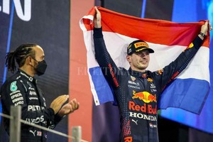 ELLITORAL_424378 |  Gentileza Max Verstappen de Red Bull celebra ganar la carrera y el campeonato mundial con la bandera de Holanda en el podio mientras Lewis Hamilton, de Mercedes, luce abatido después de terminar segundo.