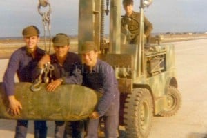ELLITORAL_447661 |  Gentileza. En plena tarea, Marcelo posa con sus compañeros, con una de las bombas que armaban en la base aérea de Trelew.