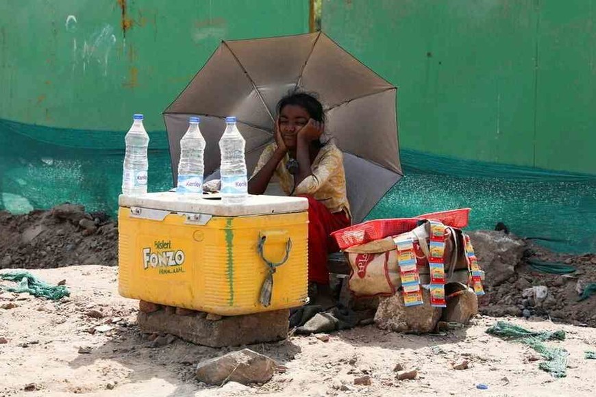 ELLITORAL_453492 |  Reuters Una chica que vende agua utiliza un paraguas para protegerse del sol, en Nueva Delhi, India, el 27 de abril de 2022.
