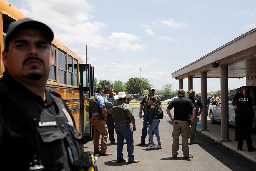 A child gets on a school bus as law enforcement personnel guard the scene of a shooting at Robb Elementary School in Uvalde, Texas, U.S. May 24, 2022.  REUTERS/Marco Bello