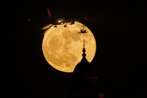 A southwest airline commercial aircraft approaches to land as a strawberry super moon rises behind the California Tower, at Balboa Park in San Diego, California , U.S., June 14, 2022.    REUTERS/Mike Blake