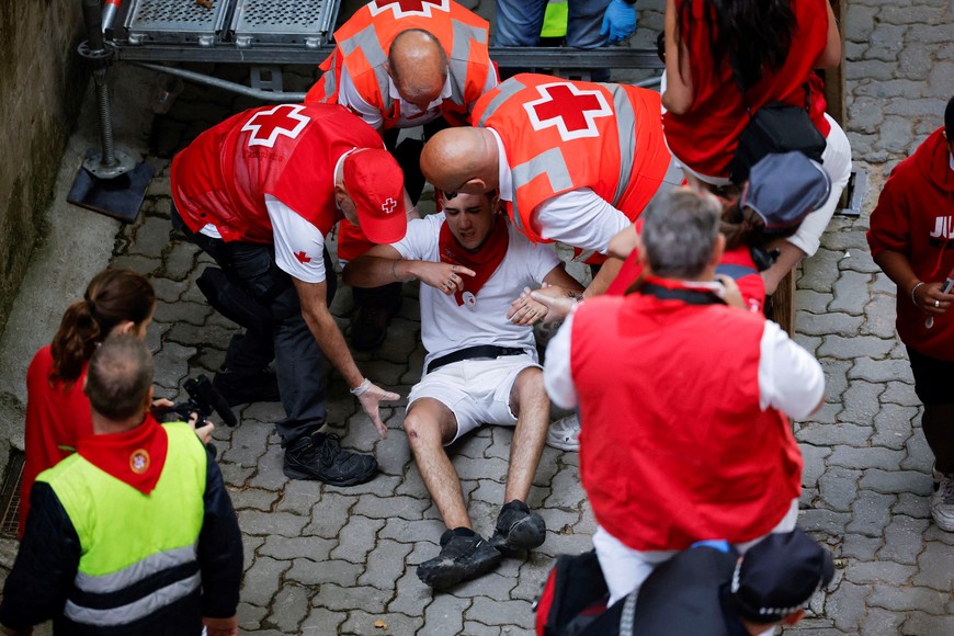 A reveller is helped by medical staff during the running of the bulls at the San Fermin festival in Pamplona, Spain, July 14, 2022. REUTERS/Juan Medina