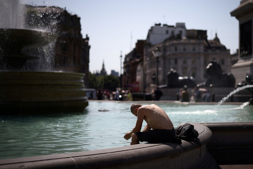 A man cools off in a water fountain during a heatwave, at Trafalgar Square in London, Britain, July 19, 2022. REUTERS/Henry Nicholls