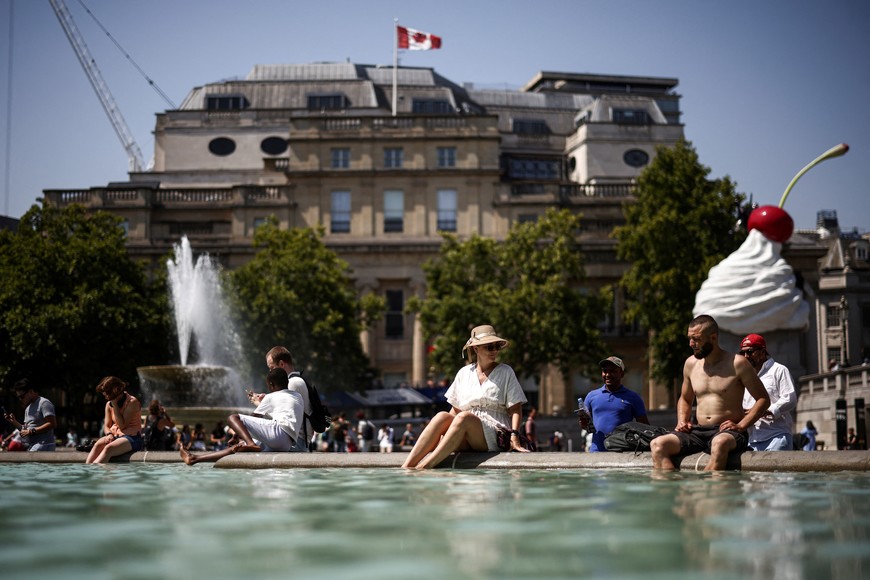 People cool off in a water fountain during a heatwave, at Trafalgar Square in London, Britain, July 19, 2022. REUTERS/Henry Nicholls