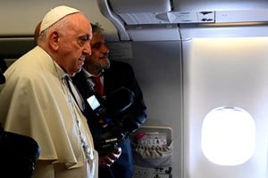 Pope Francis poses next to a journalist on board a flight heading to Edmonton International Airport in Alberta, Canada, July 24, 2022. Vincenzo Pinto/Pool via REUTERS